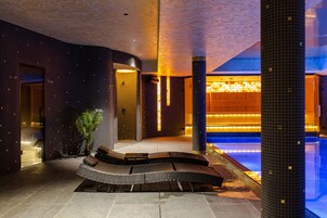 Un vestíbulo moderno con una zona de estar curvada, una piscina e iluminación ambiental cálida.