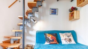 A compact room with a blue bed, a wooden staircase, and a small wooden table. - Rond Point des Pistes (Val Claret) by Interhome (Tignes)