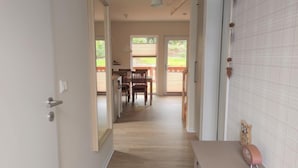 A hallway with a wooden floor leading to a dining area with a table and chairs. - Waldoase by Interhome (Bad Arolsen)