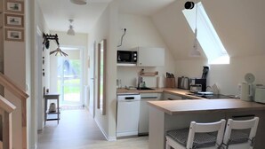 A modern kitchen with a central island, white cabinetry, and a skylight. - Waldoase by Interhome (Bad Arolsen)