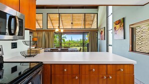 Una cucina moderna con pensili in legno, un forno a microonde in acciaio inox e un'isola grande.