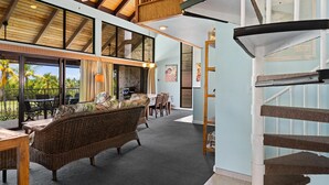 Un'ampia zona giorno con soffitto alto, una scala e vista sull'esterno.