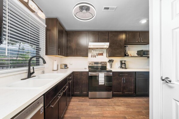 A modern kitchen with dark wood cabinets, stainless steel appliances, and a white countertop.