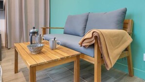 A cozy room with a wooden table, a grey sofa, a beige throw blanket, and a teal wall. - Le studio St Vincent by Interhome (Saint Malo)