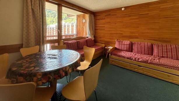 A room with a round table, chairs, a sofa, and a window with curtains. - 100m from ski slopes, 6th floor, view ski slopes, swimming pool, balcony, tv, ski locker, 35m² (La Plagne)