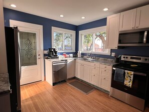 A modern kitchen with white cabinets, a black refrigerator, a built-in oven, and a microwave. - The Homecoming in Highmore, SD (Highmore)