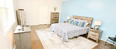 A bedroom with a bed, bedside tables, a dresser, a mirror, and a window.