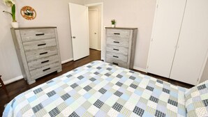 Une chambre à coucher avec un lit, deux commodes, une porte et une petite plante en pot.