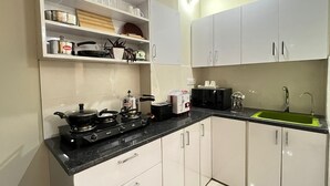 Una cocina compacta con armarios blancos, una estufa a gas, un microondas y un fregadero.