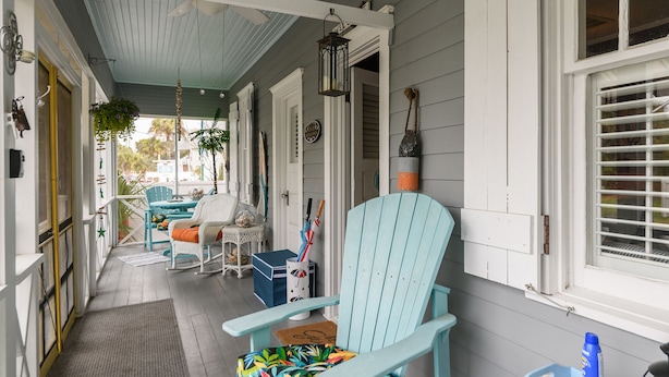 A porch with a light blue chair, a table, and a hanging lantern. - Ms. Opal's Cottage - POOL! Pet-Friendly! Ground Level (Tybee Island)