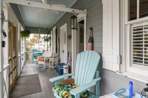Eine Veranda mit einem hellblauen Stuhl, einem Tisch und einer hängenden Laterne.