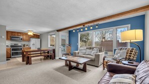 A spacious living room with a brown leather sofa, a wooden coffee table, and a blue accent wall. - 4 story condo - 100 yard walk to slopes on Sugar Mountain (Sugar Mountain)