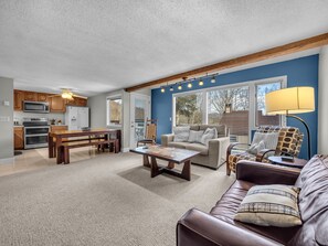 Enjoy meals in the dining area with a wooden table and bench, or relax in the living room with a comfortable sofa and armchair.