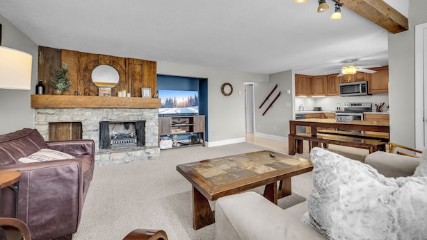 A living room with a stone fireplace, leather sofa, and a wooden coffee table. - 4 story condo - 100 yard walk to slopes on Sugar Mountain (Sugar Mountain)