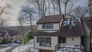 A two-story house with a garage, a covered porch with chairs, and a driveway. - 4 story condo - 100 yard walk to slopes on Sugar Mountain (Sugar Mountain)