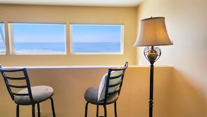 A room with two chairs facing a window overlooking the ocean, a floor lamp, and a beige wall. - Nye Beach Ocean Front Condo! Walk to Everything! Spectacular Views! (Newport)