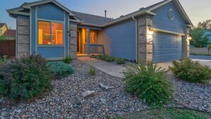 Einbungalow mit Garage, einer Veranda und einem gepflegten Garten mit Steinen und Sträuchern.