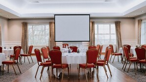 A conference room with a large table, red chairs, and a projector screen. - Edenmore Golf and Country Club (Craigavon)