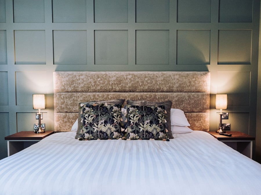 A neatly made bed with a striped bedspread, two nightstands with lamps, and a headboard with a floral pattern.