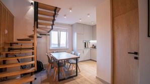 Una cucina moderna con zona pranzo, scala in legno e vista sulla città.
