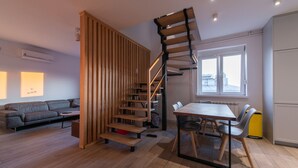 Un interno moderno con una scala in legno, una zona pranzo e un divano.