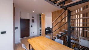 Un interno moderno con un tavolo da pranzo in legno, una scala con ringhiera in legno e un angolo studio.
