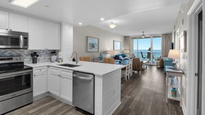 A modern kitchen with stainless steel appliances, a central island, and a dining area with a view of the ocean.
