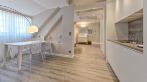 A modern kitchen with a built-in oven and a dining area with a table and chairs. - Living am Carlsplatz (Düsseldorf)