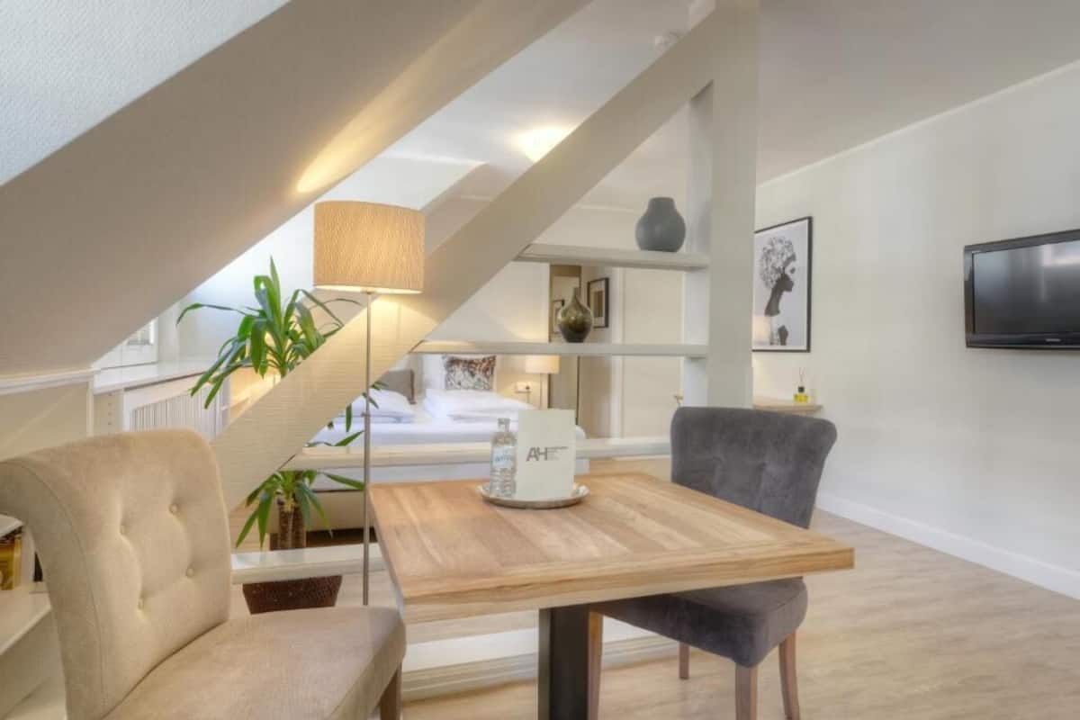 Ein modernes Wohnzimmer mit einem Holztisch, zwei Stühlen, einer Lampe und einer Treppe.