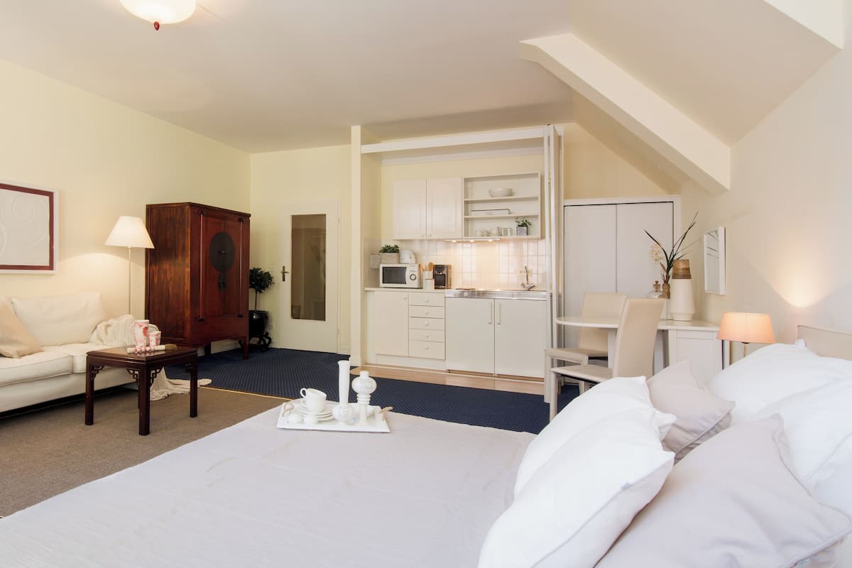 Ein Hotelzimmer mit einem Bett, einem kleinen Tisch mit Tablett, einem Holzschrank, einer Küchenzeile und einem Schreibtisch mit Stuhl.