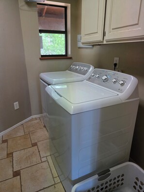 A laundry room with two front-loading washing machines, a window, and a laundry basket.