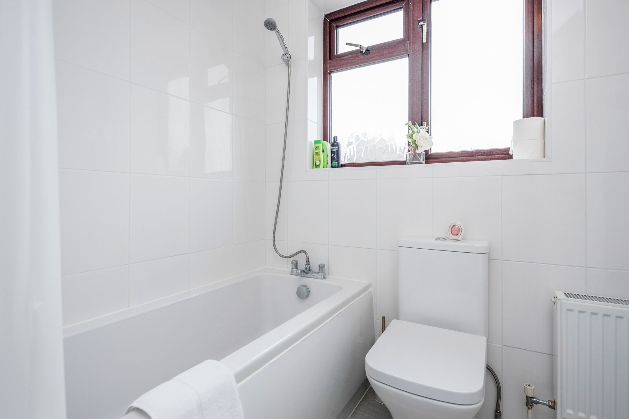 A bathroom with a bathtub, toilet, and a window.