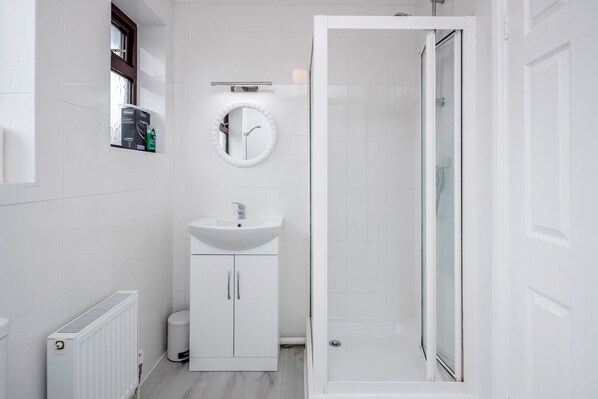A modern bathroom with a white sink, mirror, and shower.
