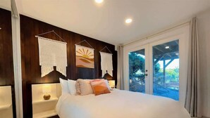 A modern bedroom with a large bed, a nightstand, and a wall-mounted macrame piece. - Pano Water View, Fab Deck, Rec Room, King Bed (Port Angeles)