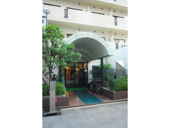 Enter a stylish hotel with a curved glass canopy and a welcoming green area.