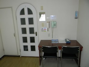 Simple room with a desk, chairs, and telephone.