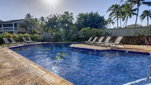 A swimming pool with lounge chairs, palm trees, and a building in the background. - Turtle Bay Golf Course View. Updated 1-bed w/*AC, covered lanai, end unit (Kahuku)