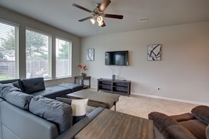 A modern living room with a sectional sofa, a coffee table, and a TV mounted on the wall. - Romantic 3-BR Townhouse With Backyard ~ Double Story - Pet Friendly! (Rosenberg)