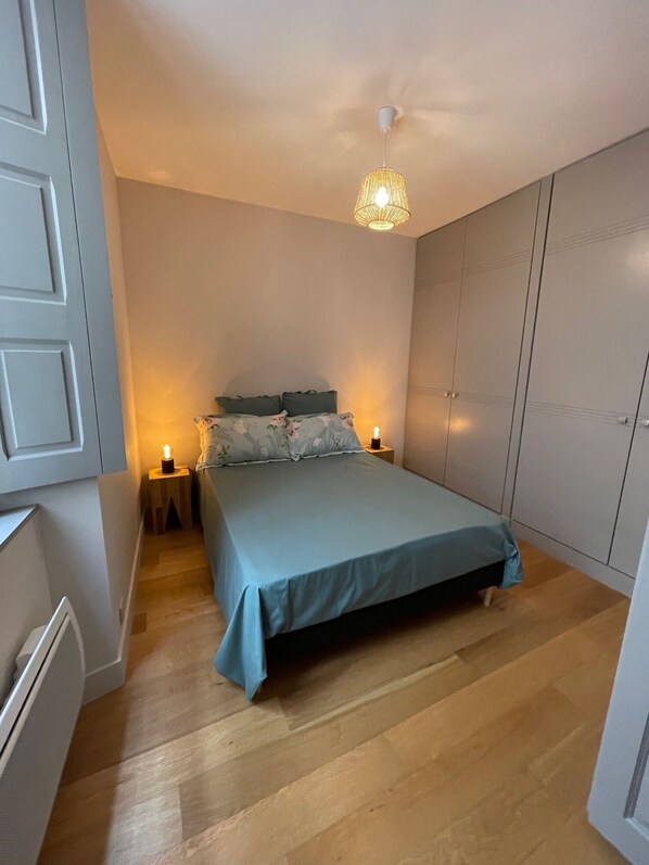 Ein Schlafzimmer mit Bett, Nachttischen, einem Kleiderschrank und einer Deckenleuchte.