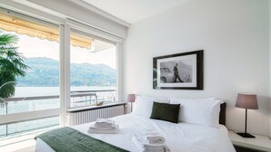 Hotelkamer met een groot bed, uitzicht op zee, een ingelijst schilderij aan de muur en een lamp op het nachtkastje.