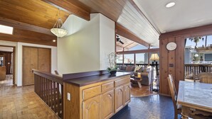 A spacious kitchen with wooden cabinetry, a dining area with a table and chairs, and a view of the outdoors. - 221W: Family Friendly Avalon Home, Golf Cart, Large Deck + Outdoor Dining (Avalon)