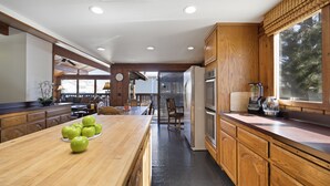 A modern kitchen with wooden cabinets, a large island with apples, and a view of the outdoors. - 221W: Family Friendly Avalon Home, Golf Cart, Large Deck + Outdoor Dining (Avalon)