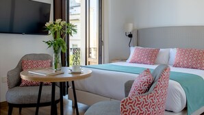 Ett hotellrum med en säng, en tv, ett bord med en vas med blommor och en stol.