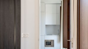 Une cuisine moderne avec des armoires blanches, un four encastré et un petit plan de travail.