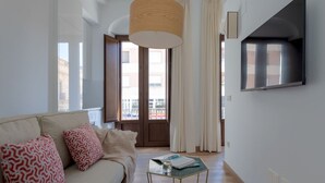 Un salon moderne avec un canapé, une table basse, une grande fenêtre et un téléviseur fixé au mur.