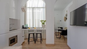 Et moderne køkken med hvide skabe, indbygget ovn og et spiseområde med to stole og et bord.