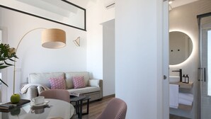 Een moderne woonkamer met een bank, een rond glazen tafeltje en gestreept fauteuils.