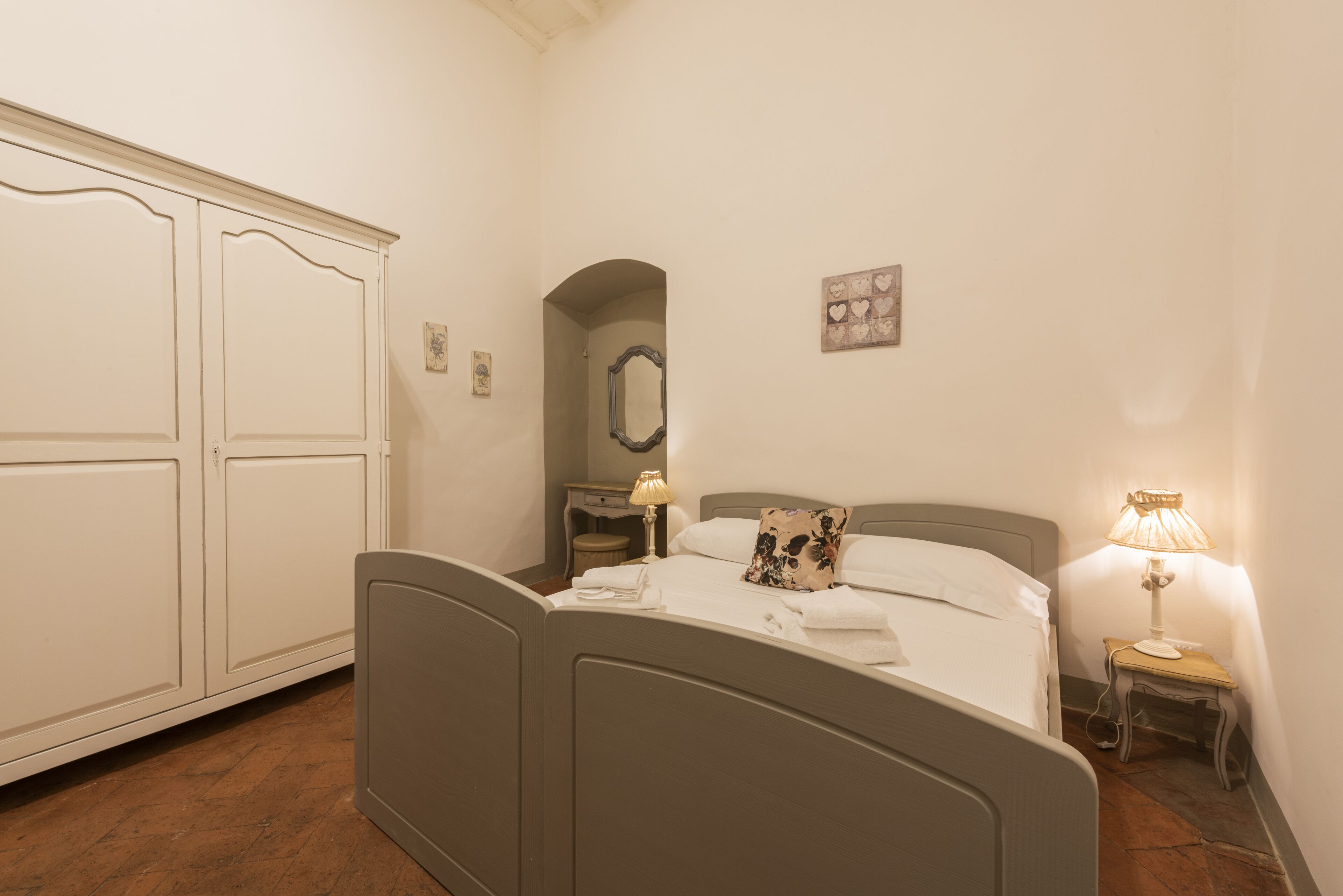 A bedroom with a bed, bedside table, lamp, and wardrobe.