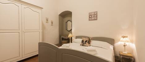 A bedroom with a bed, bedside table, lamp, and wardrobe.
