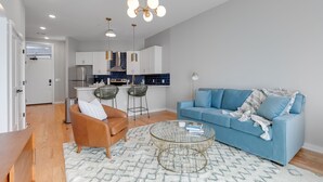 A modern living room with a blue sofa, a brown leather chair, and a glass coffee table.